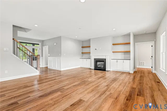 an empty room with wooden floor fireplace and windows