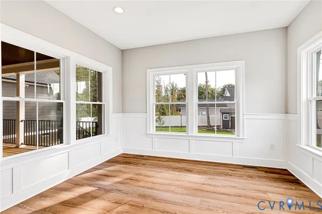 a view of an empty room with a window and wooden floor