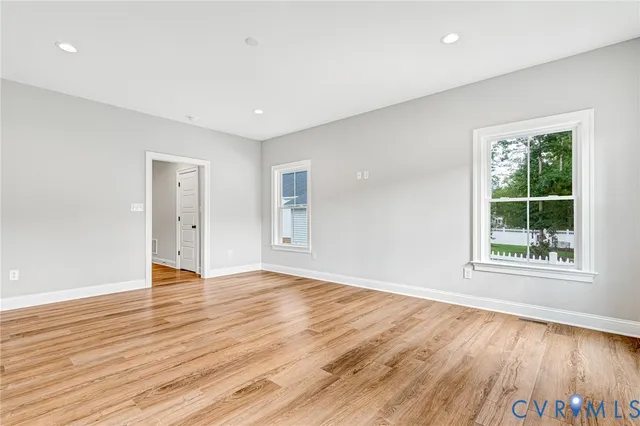 an empty room with wooden floor and windows