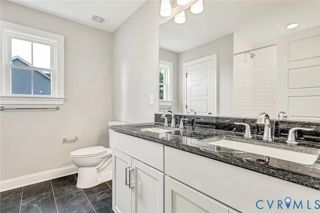 a bathroom with a granite countertop sink toilet and mirror