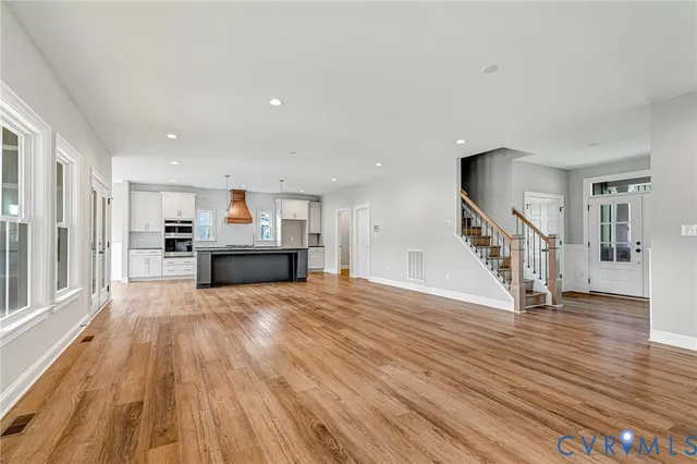 a view of a living room with wooden floor and stairs