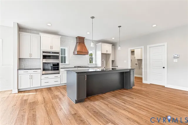 a kitchen with stainless steel appliances kitchen island granite countertop a stove a sink and white cabinets