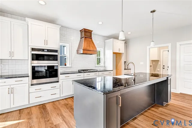 a kitchen with stainless steel appliances granite countertop a sink a stove and a refrigerator