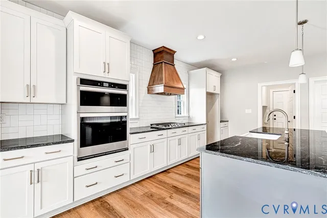 a kitchen with granite countertop a stove and white cabinets