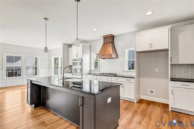 a kitchen with stainless steel appliances granite countertop a sink a stove and a wooden floors