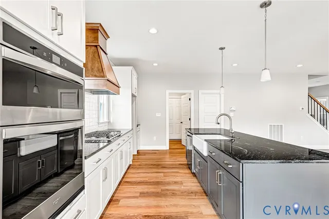 a large kitchen with stainless steel appliances granite countertop a lot of cabinets and wooden floor