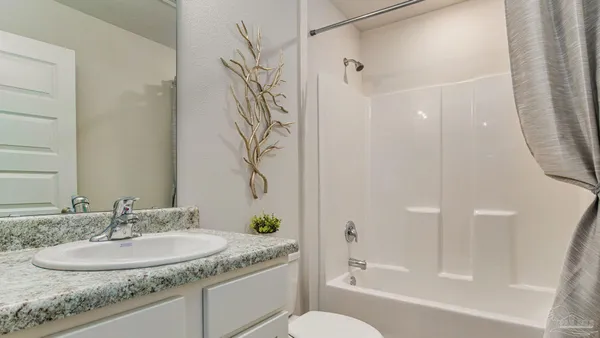 a bathroom with a granite countertop sink a toilet and shower