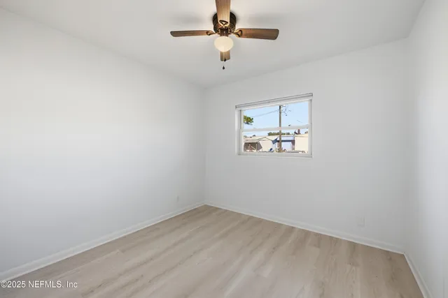 an empty room with a window and ceiling fan