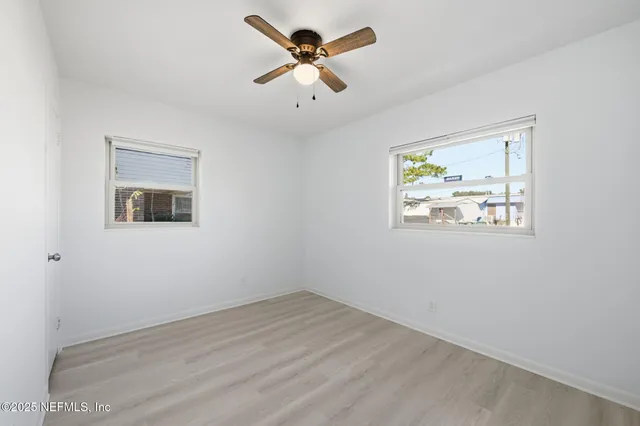 an empty room with wooden floor and ceiling fan