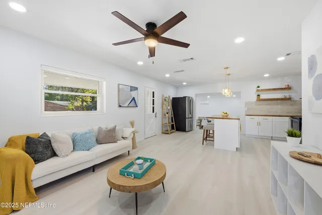 a living room with furniture kitchen view and a window