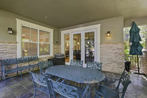a patio with table and chairs and potted plants