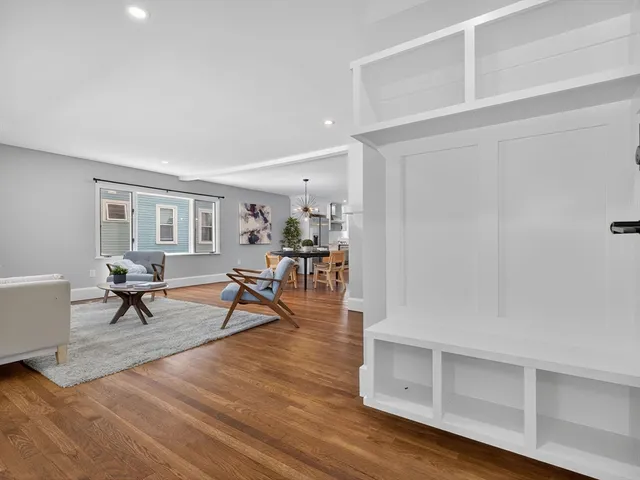 a living room with furniture and a dining table with wooden floor