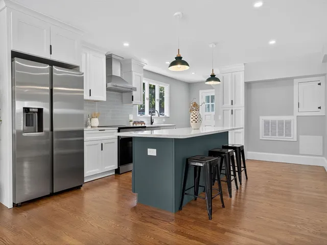 a kitchen with stainless steel appliances granite countertop a table chairs refrigerator and sink