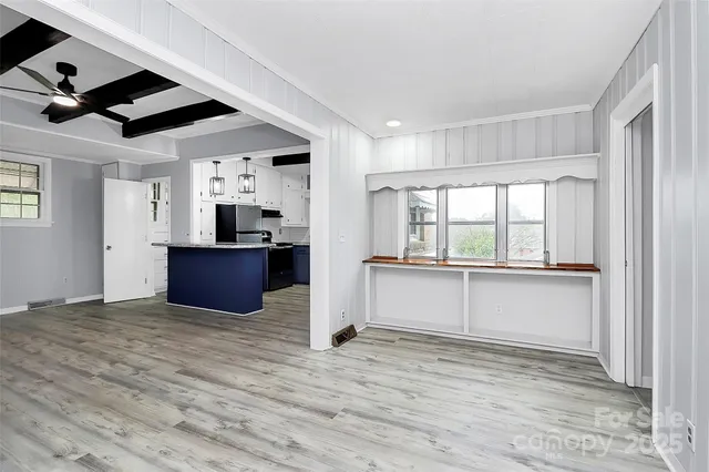 a view of an empty room with window and wooden floor