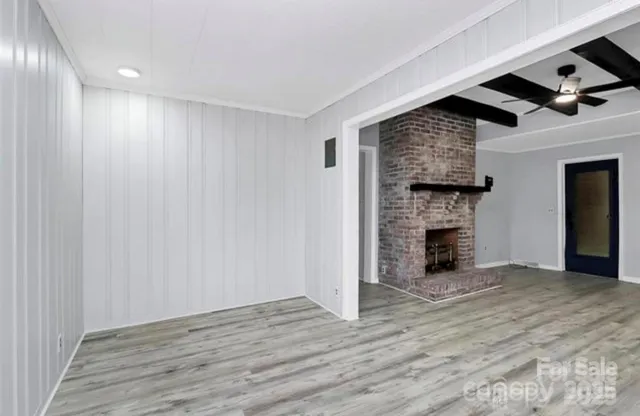 a view of an empty room with wooden floor and a fireplace