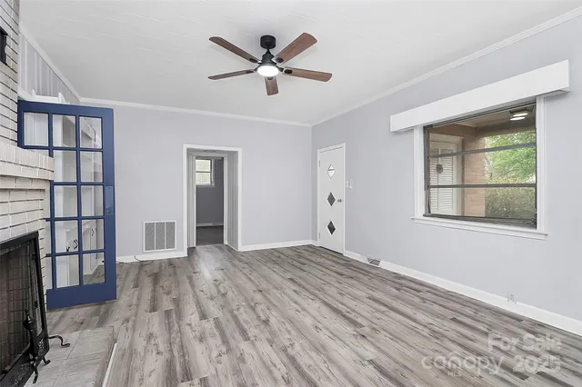 a view of empty room with wooden floor and fan