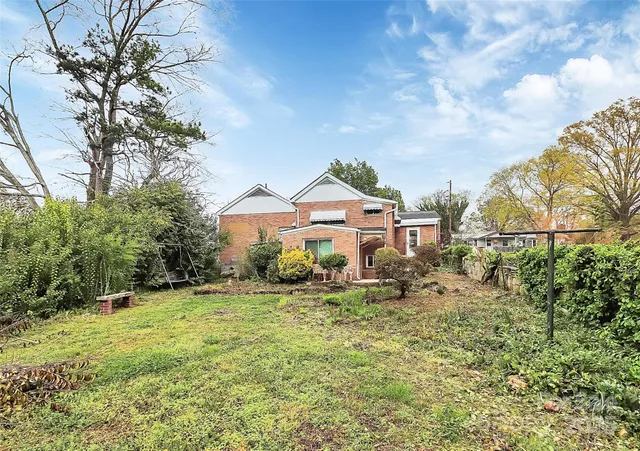 a backyard of a house with plants and large tree