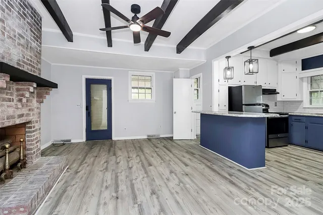 a view of kitchen and empty room with fireplace