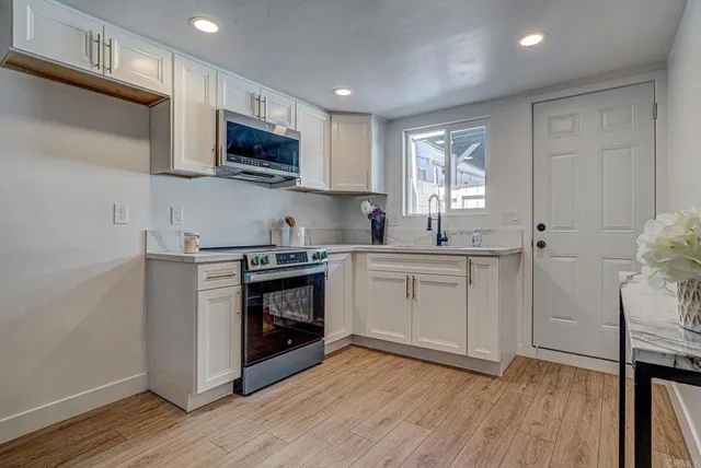 a kitchen with stainless steel appliances a white stove top oven sink and cabinets