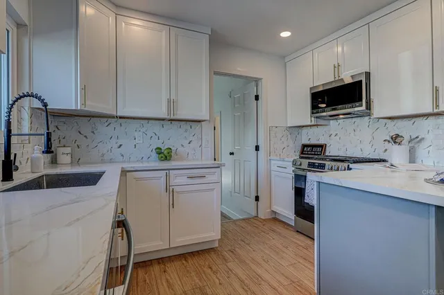 a kitchen with stainless steel appliances granite countertop a sink stove and microwave