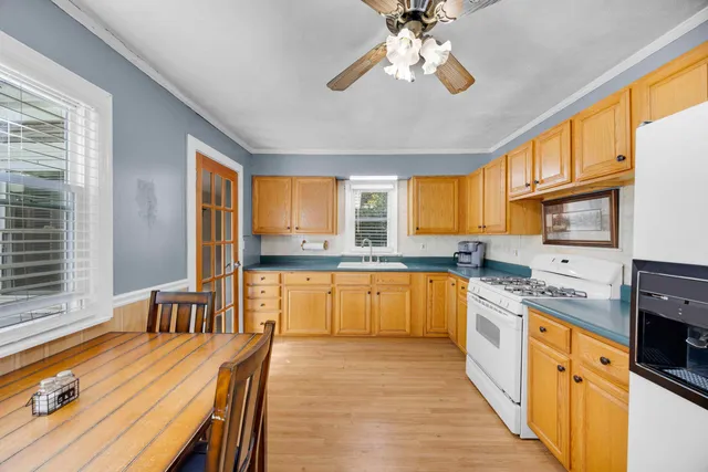 a kitchen with stainless steel appliances granite countertop a stove a sink dishwasher a dining table and chairs with wooden floor