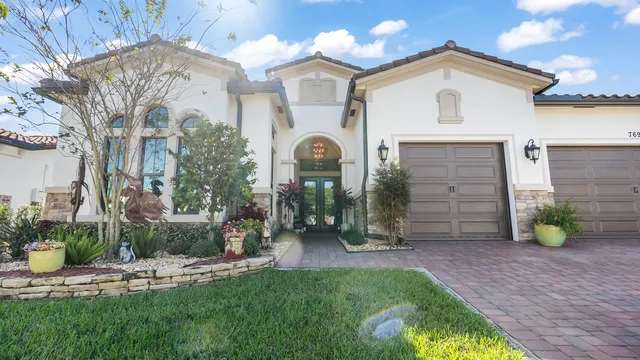a view of a house with a small yard and a large tree