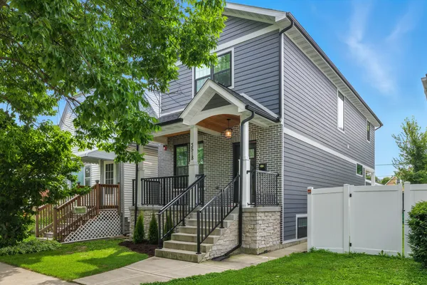 a view of a house with a small yard and a large tree