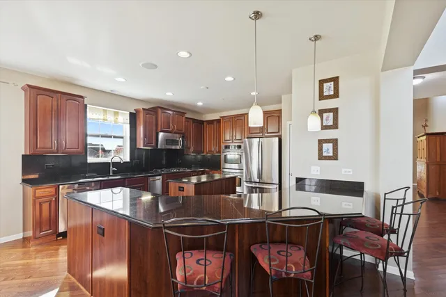 a kitchen with stainless steel appliances granite countertop a stove a refrigerator a kitchen island a table and chairs