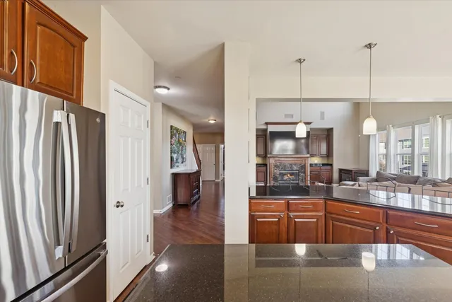 a kitchen with stainless steel appliances granite countertop a refrigerator and a view of living room