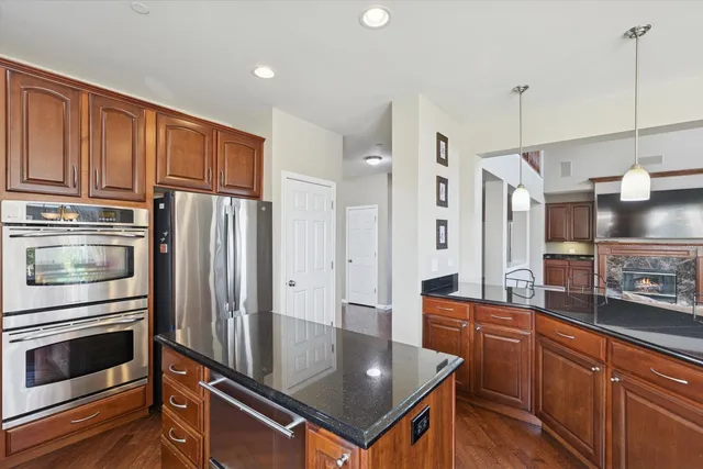 a kitchen with stainless steel appliances granite countertop a refrigerator a stove and a sink with wooden floor