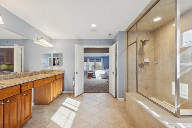 a large en suite bathroom with a granite countertop sink mirror and shower
