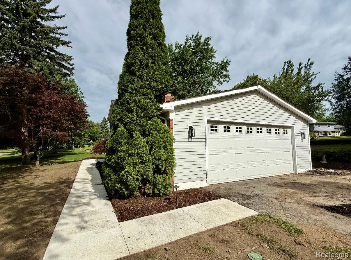 2360 Oklahoma Avenue Rochester, MI 48309 - Photo 5 of 36 Attached two-car garage with light gray siding and decorative outdoor lighting