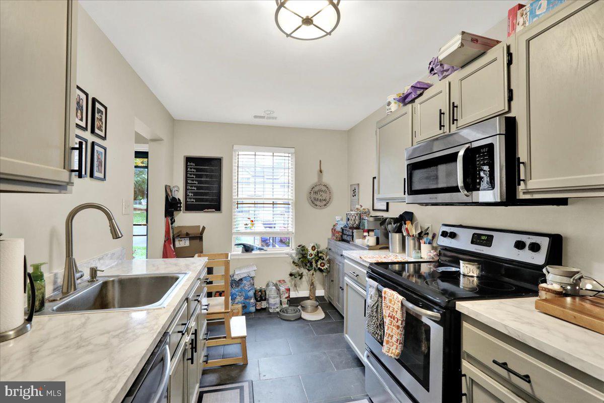 120 Laurel Court Reading, PA 19610 - Photo 9 of 21 a kitchen with stainless steel appliances a stove a sink dishwasher a microwave oven with a dining table and chairs