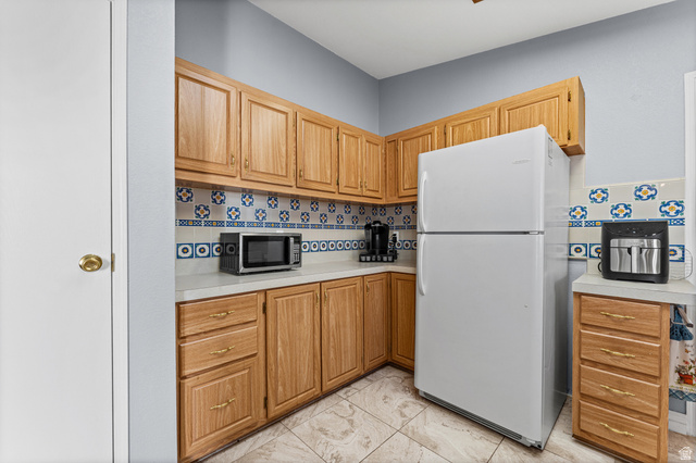 312 Harriger Way Layton, UT 84041 - Photo 19 of 36 Kitchen featuring abundant wood cabinetry, patterned tile backsplash, and light-toned countertops