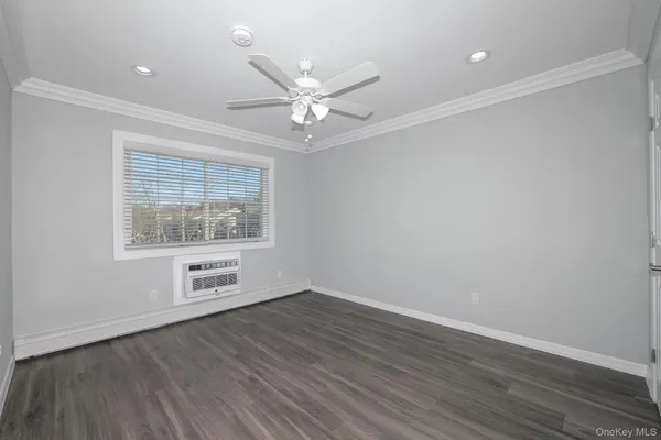 an empty room with wooden floor chandelier fan and windows
