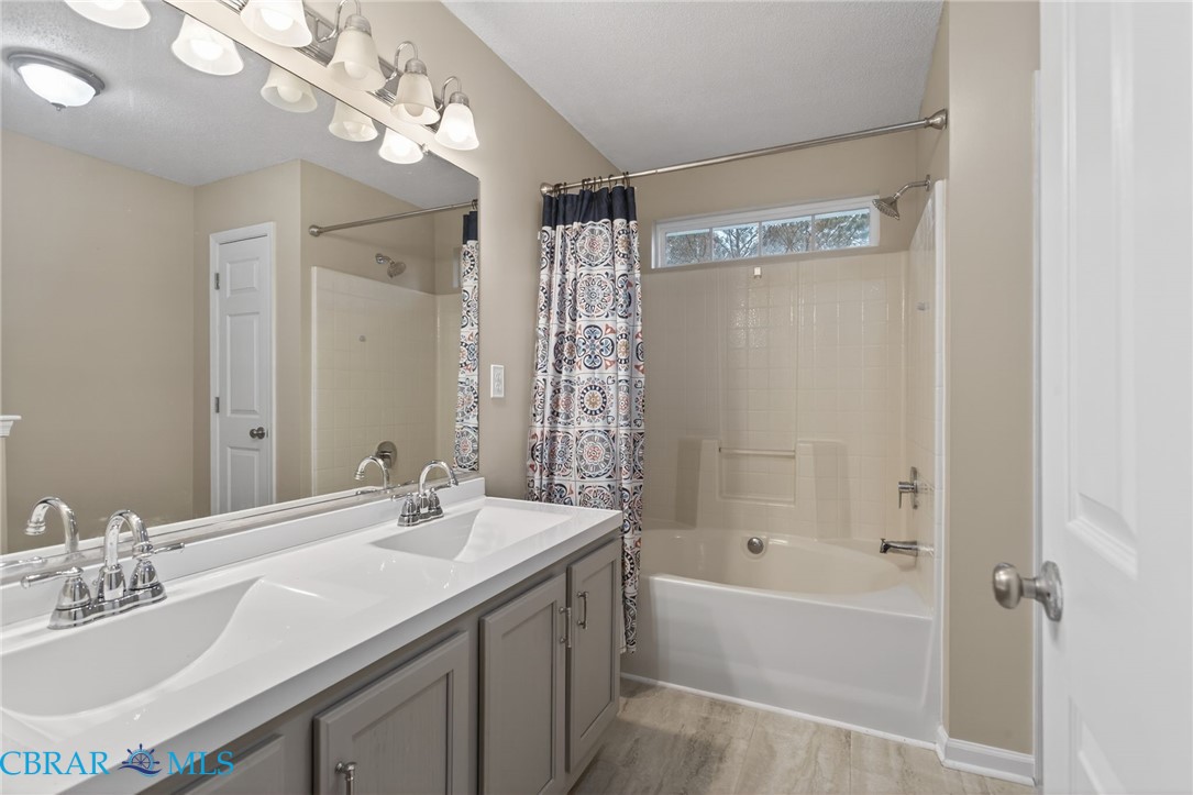 116 Old Field Road Williamsburg, VA 23188 - Photo 21 of 27 Bathroom featuring double vanity, shower / bathtub combination with curtain, and light wood-style floors