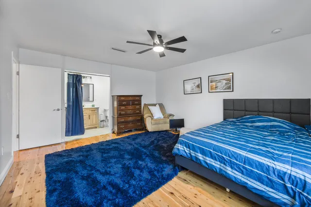 a bedroom with a bed and dresser with wooden floor