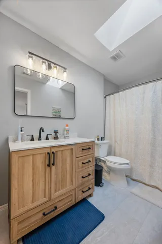 a bathroom with a double vanity sink a toilet and a mirror