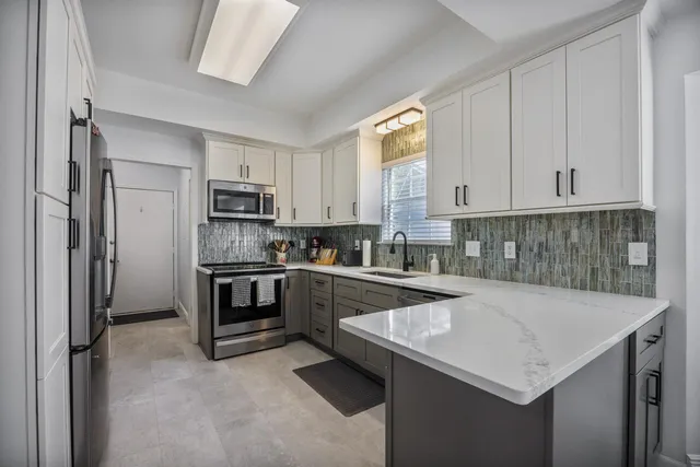 a kitchen with a sink a stove a refrigerator and white cabinets