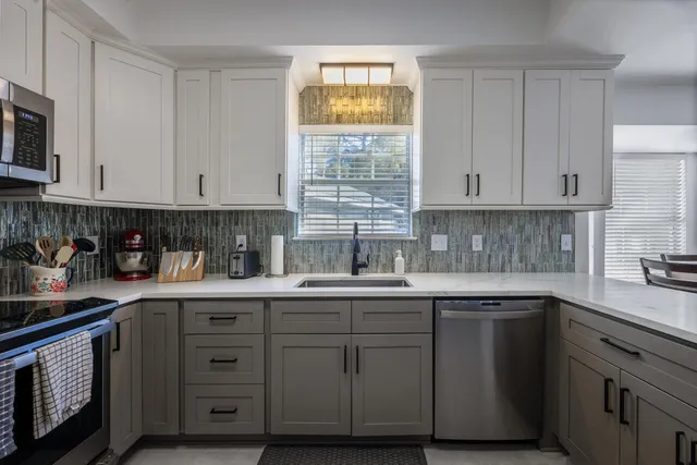 a kitchen with cabinets appliances a sink and a window