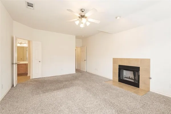 a view of an empty room with chandelier fan and fire place