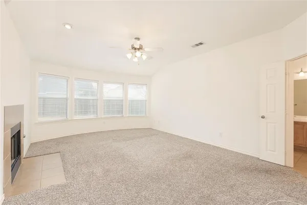 an empty room with chandelier fan and windows
