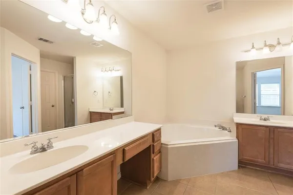 a bathroom with a tub a sink and mirror