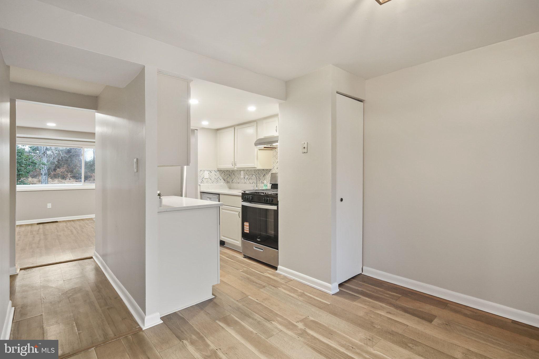 9432 Merryrest Road Columbia, MD 21045 - Photo 9 of 47 a kitchen with white cabinets and wooden floor