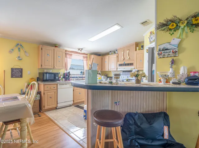 a kitchen with granite countertop a table chairs stove top oven and sink