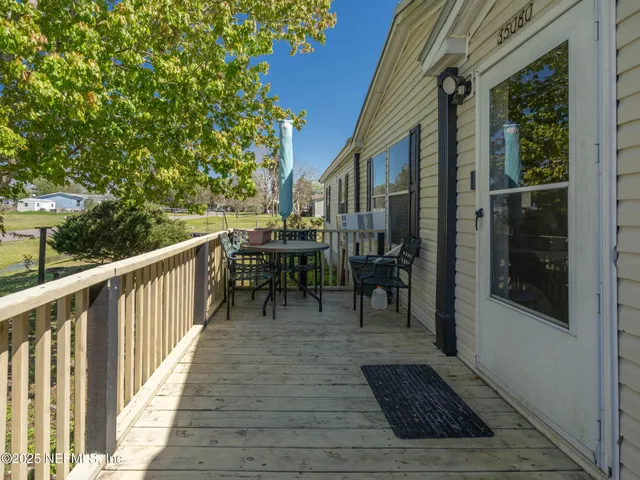 a view of a patio with table and chairs with wooden floor and fence