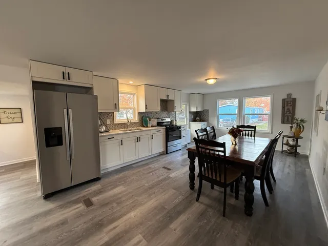 a kitchen with a dining table chairs refrigerator and cabinets