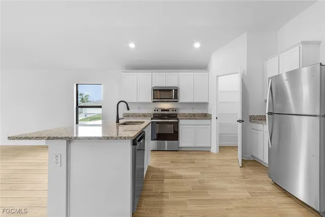 a kitchen with stainless steel appliances granite countertop a refrigerator sink and stove