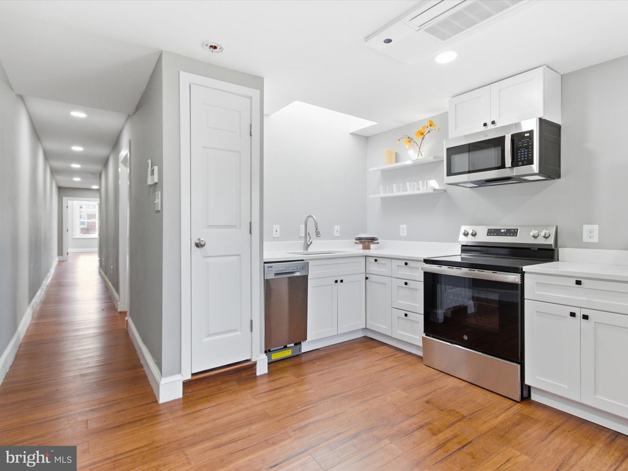 2617 13th Street Northwest, Unit PH Washington, DC 20009 - Photo 3 of 12 a kitchen with stainless steel appliances a white stove top oven and cabinets