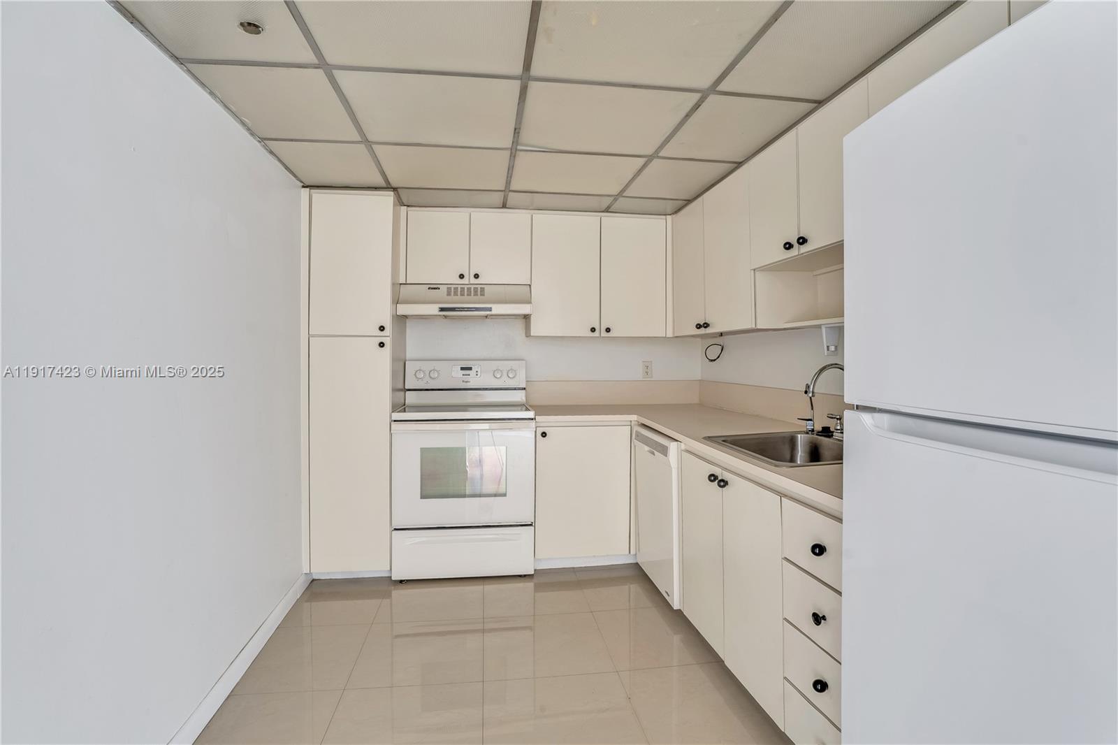 1200 St Charles Place, Unit 716 Pembroke Pines, FL 33026 - Photo 9 of 29 a kitchen with white cabinets and white appliances